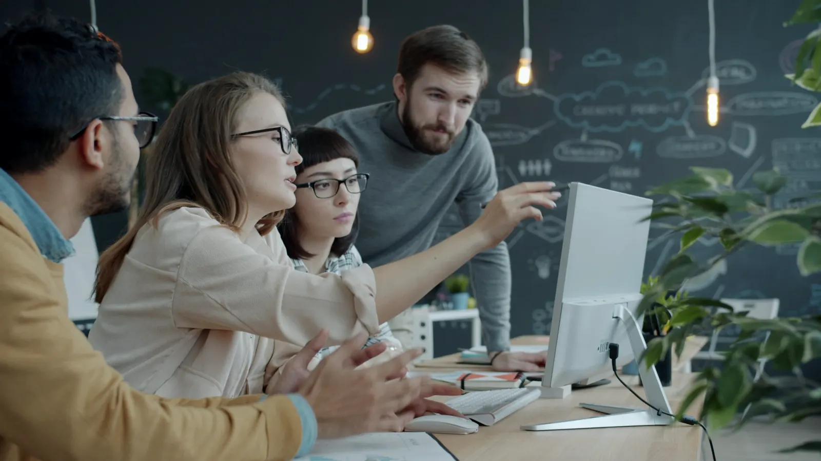 A team of colleagues discussing work together around a computer