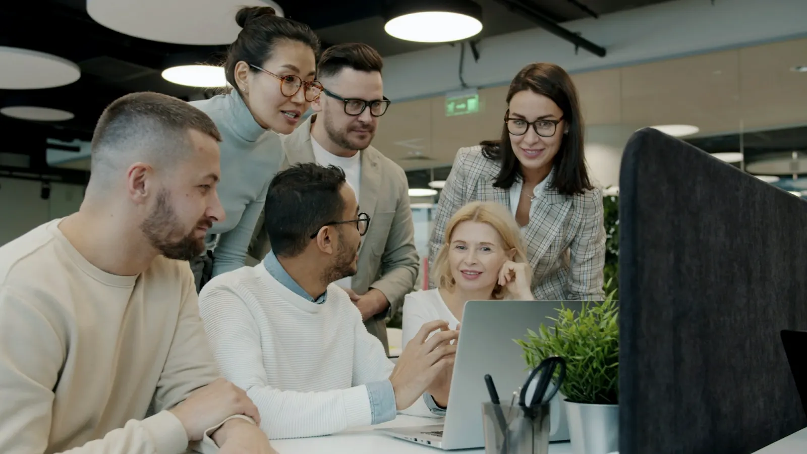 A diverse team celebrating progress around a laptop